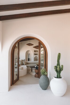 Un arco de entrada a un salón con un sofá, una planta de cactus y una mesa redonda.