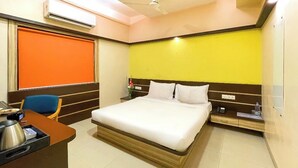 Une chambre d’hôtel équipée d’un lit, d’un bureau avec une machine à café, d’une chaise, d’un climatiseur et d’un ventilateur de plafond.