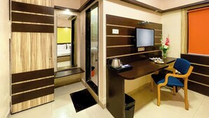 Une chambre d’hôtel moderne avec un mur d’accent en bois, un bureau avec une chaise, une télévision et une petite table sur laquelle est posé un vase de fleurs.