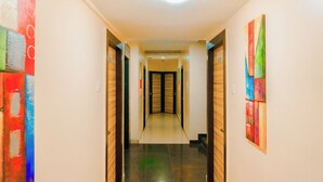 Un couloir avec des portes en bois et un sol carrelé, qui mène à une pièce dotée d’une porte en bois sombre.