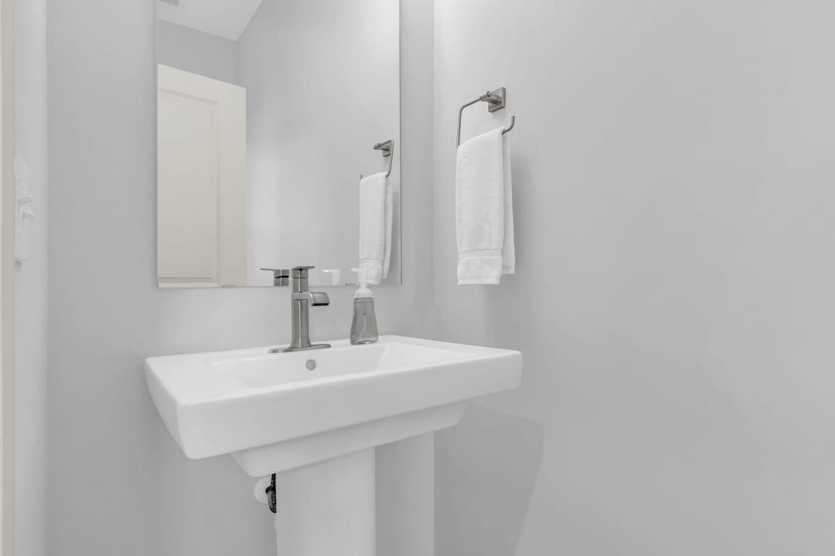 A bathroom with a white sink, a mirror, and a towel hanging on a rack.