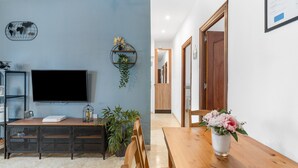 Ein Wohnzimmer mit Fernseher, Holzmöbeln, einer Pflanze und einer Blumenvase.