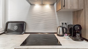 Eine moderne Küche mit eingebautem Herd, einem Wasserkocher, einer Kaffeemaschine und einem Toaster.