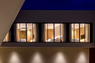 Quarto de hotel moderno com uma janela grande, uma cama e uma televisão.