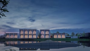 Un bâtiment moderne à étages, doté de grandes fenêtres qui se reflètent sur une étendue d’eau calme.