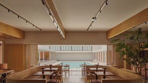 Un espace piscine intérieur moderne, doté de mobilier en bois et offrant une vue sur la piscine.