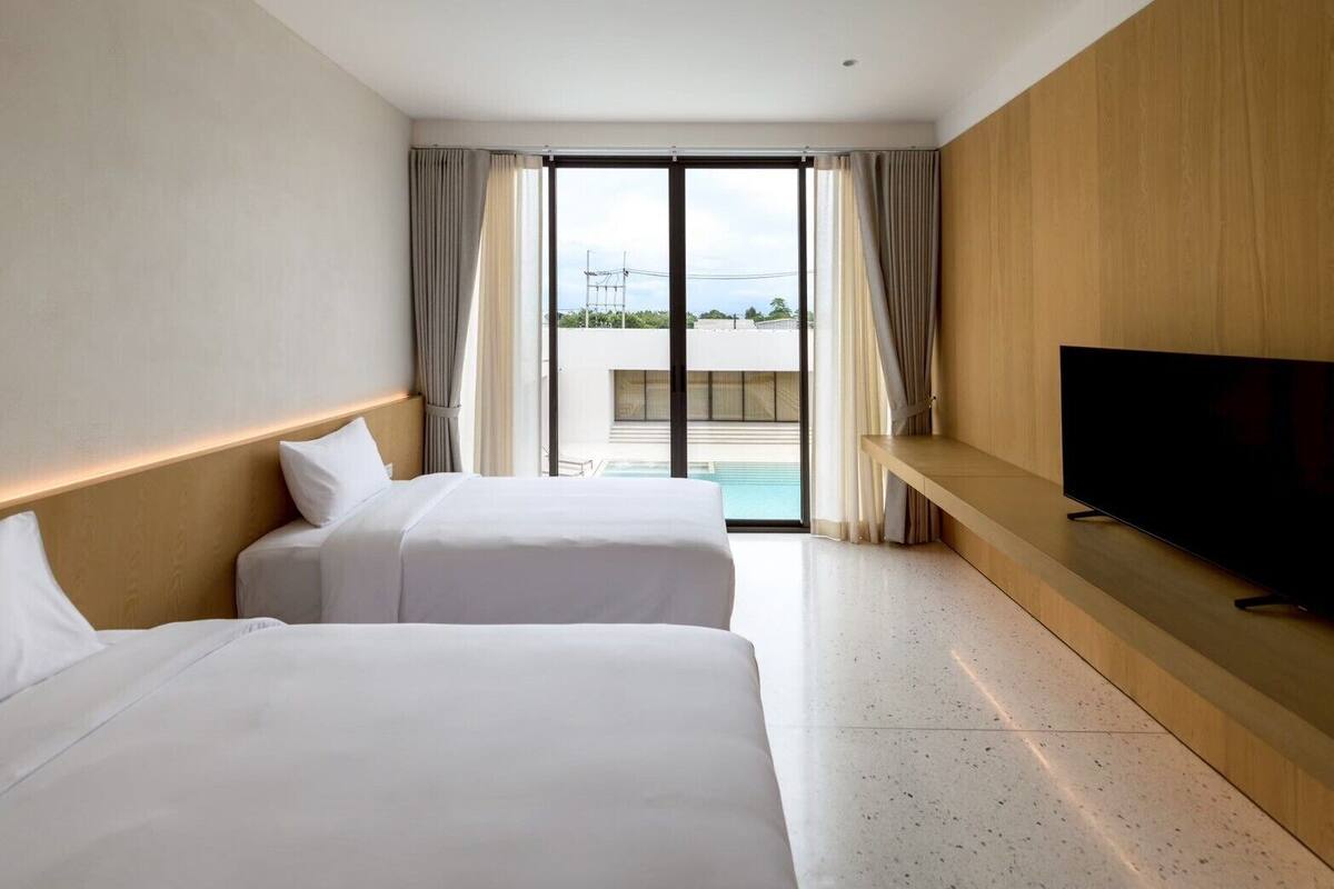 A hotel room with two beds, a TV, and a view of a swimming pool.