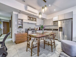 A modern kitchen with a central island, stainless steel appliances, and a dining area with wooden chairs.