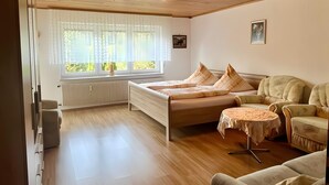 Een kamer met een bed, een bank, een klein tafeltje en een radiator.