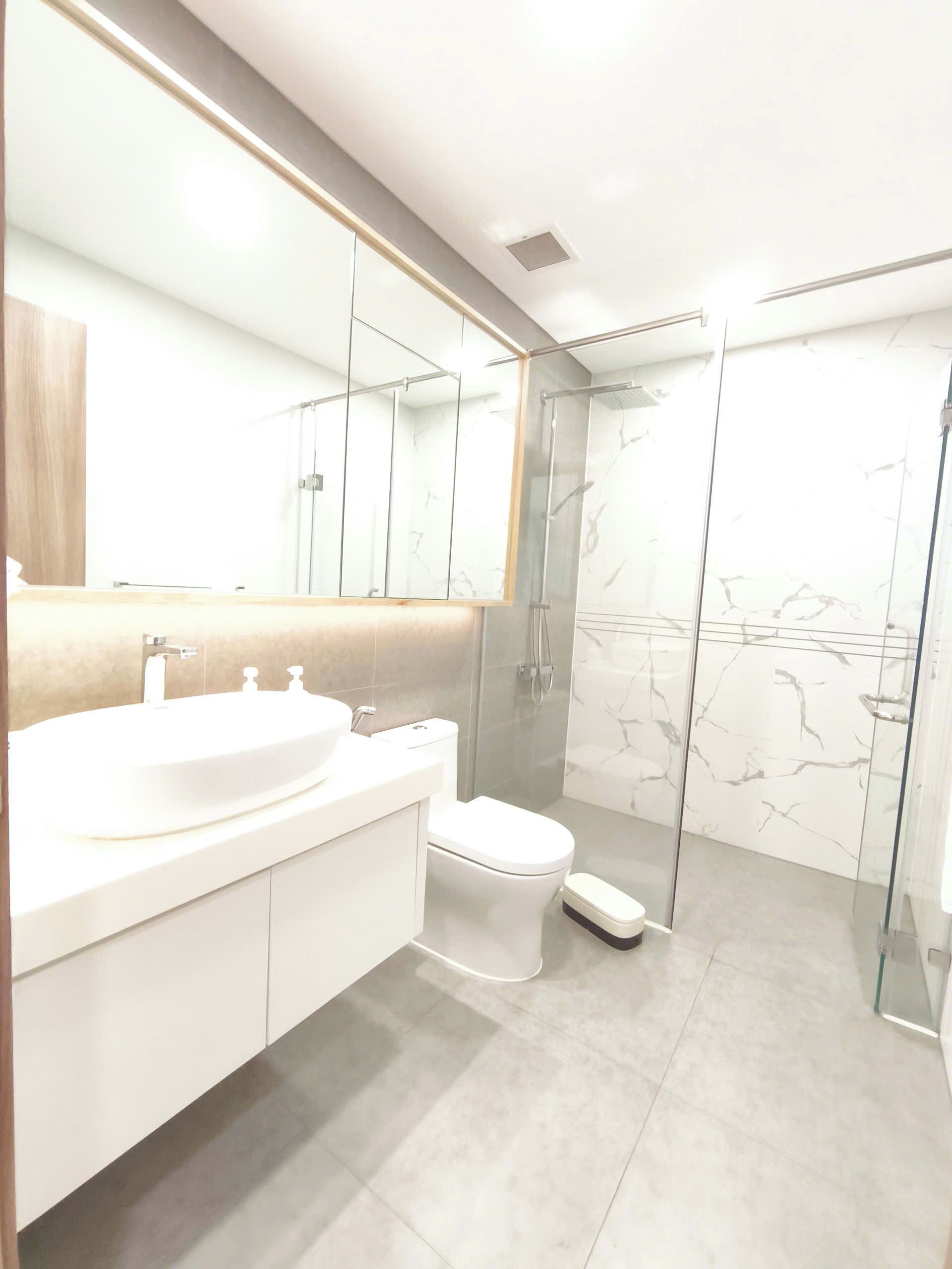 A modern bathroom with a large sink, toilet, and glass shower enclosure.