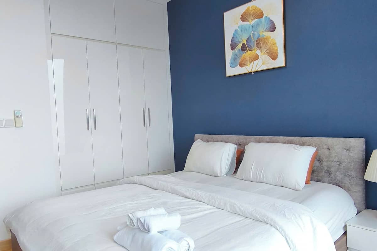 Ein Schlafzimmer mit Bett, weißem Kleiderschrank und Wandbild.