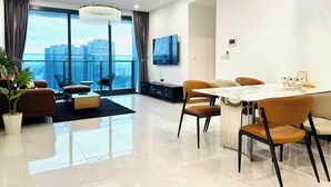 A modern living room with a dining area, large windows, a chandelier, and a flat-screen TV. - Skyway White & Silver Riverside Resident - Binh Thanh, HCM (Ho Chi Minh City)