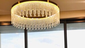 A modern room with a large window, a chandelier, and two chairs. - Skyway White & Silver Riverside Resident - Binh Thanh, HCM (Ho Chi Minh City)