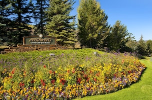 Placa do Arrowshead Country Club of the Rockies com um jardim paisagístico em primeiro plano.