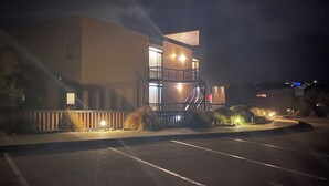 A multi-story building with a staircase, a parking lot, and a well-lit exterior. - Coastal Cove Suite with balcony - close to hot springs. (Fingal)