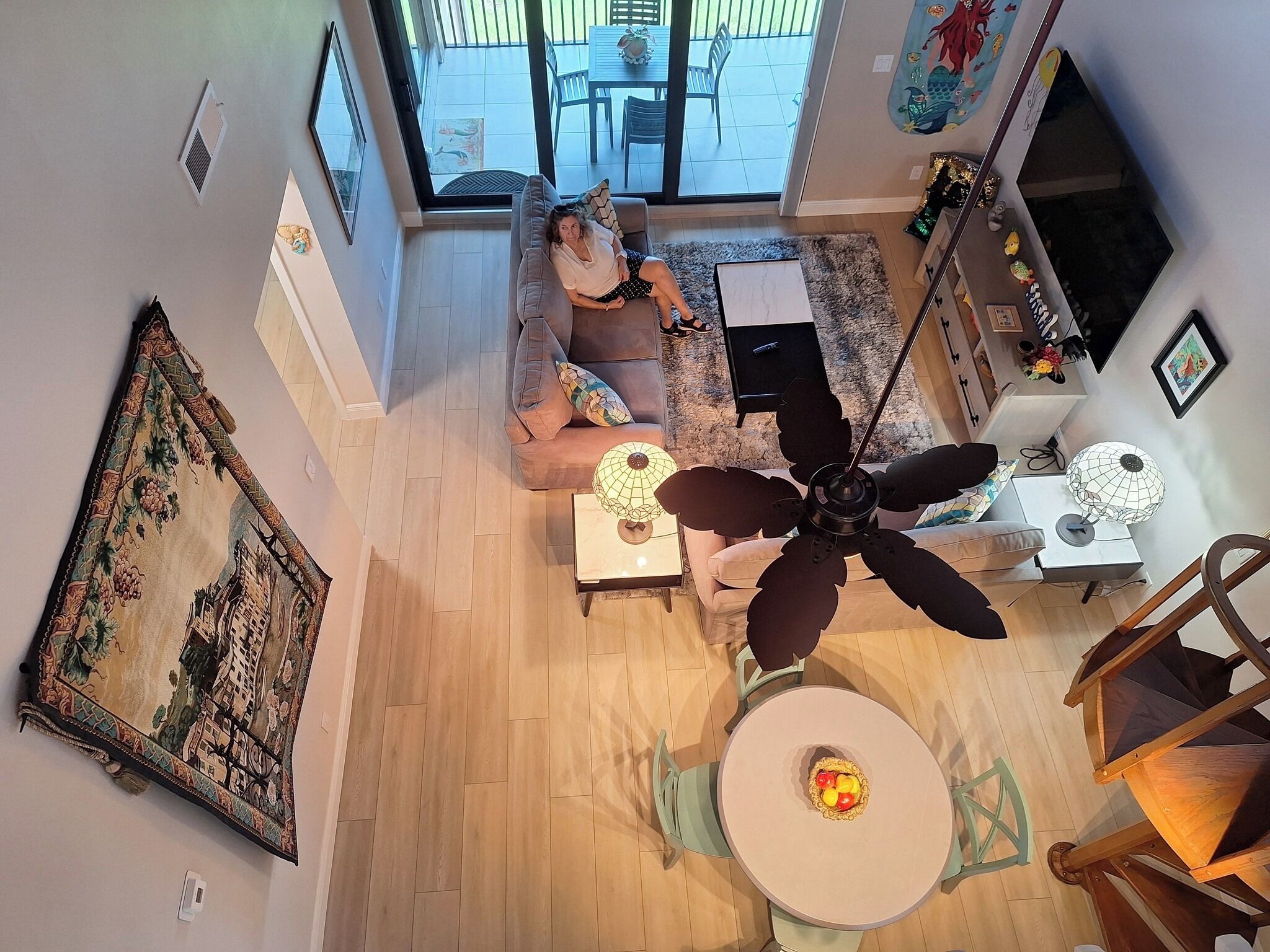 A spacious living room with a large window, a ceiling fan, and a dining area with a table and chairs.