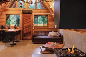 Un intérieur de chalet chaleureux, avec un revêtement en bois, une cheminée, un canapé et un coin repas.