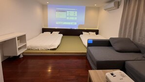 Ett hotellrum med en säng, en soffa, ett litet bord och en projektorduk där en presentation visas.