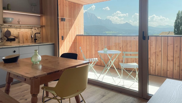 A modern kitchen with wooden cabinets and a large window overlooking a mountainous landscape. - Apartment Schwarzhorn (Barbian)