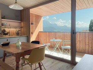 A modern kitchen with wooden cabinets and a large window overlooking a mountainous landscape. - Apartment Schwarzhorn (Barbian)
