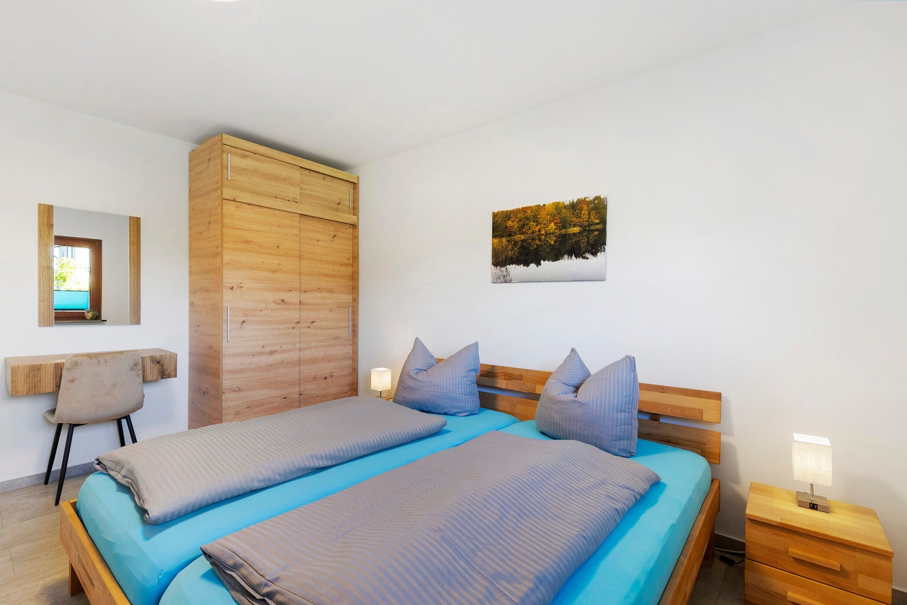 Una camera da letto con due letti, un armadio in legno, una scrivania e un comodino con una lampada.