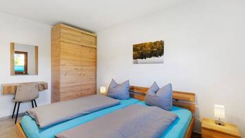 Una camera da letto con due letti, un armadio in legno, una scrivania e un comodino con una lampada.