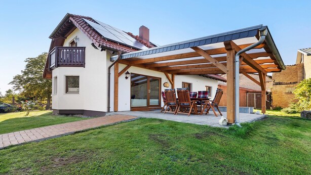 Une maison à deux étages dotée d’un patio couvert, d’un balcon et d’un chemin en briques menant à l’entrée.