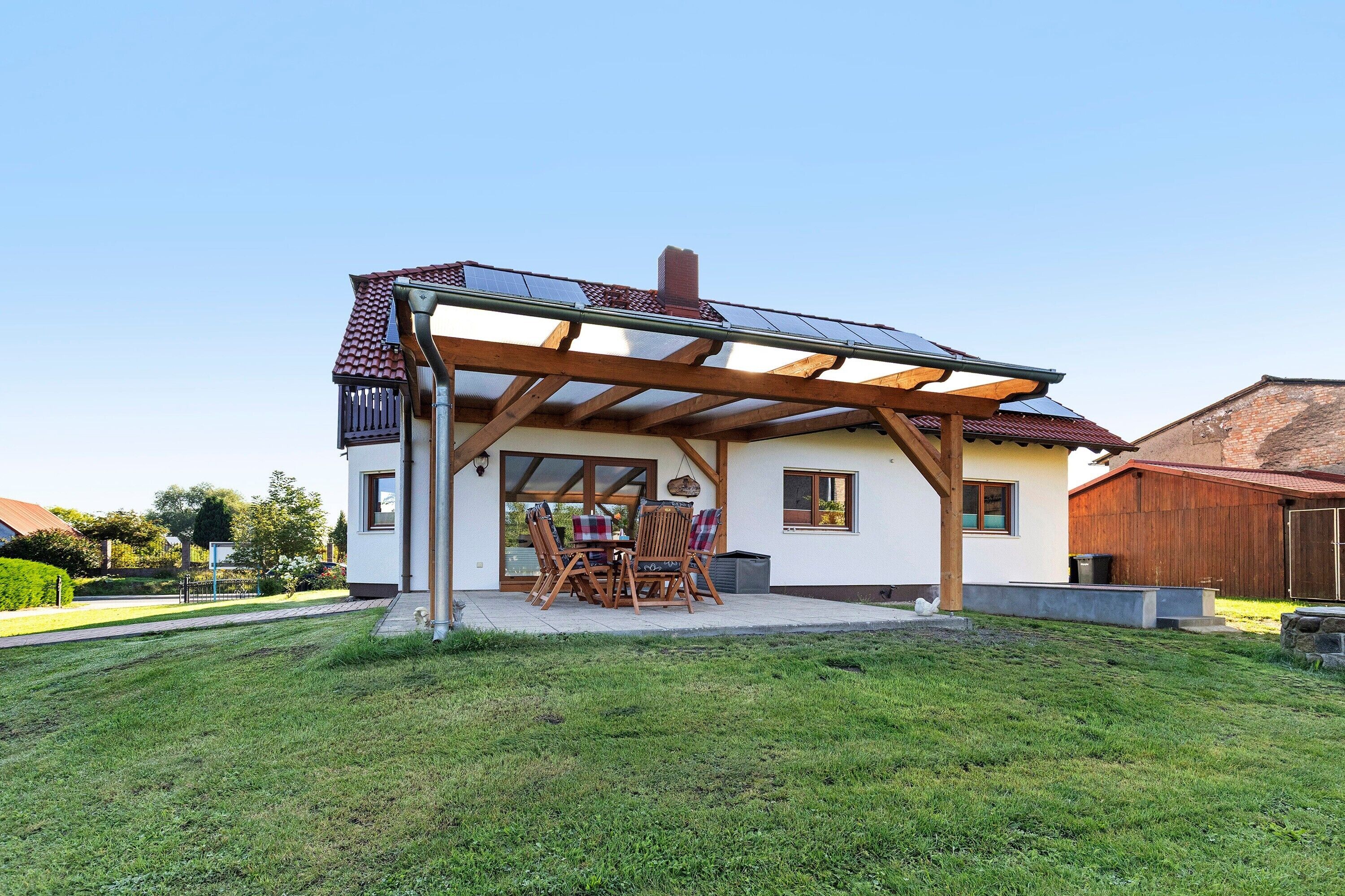 Una casa con patio coperto, tavolo e sedie da pranzo.