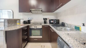 A modern kitchen with dark wood cabinets, granite countertops, stainless steel appliances, and a built-in oven. - 1209 Sky Gardens in Dubai (Dubai)