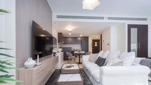 A modern living room with a white sofa, a coffee table, and a kitchen area in the background. - 1209 Sky Gardens in Dubai (Dubai)