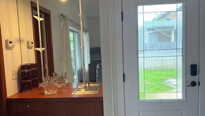 Een badkamer met een houten wastafel, een grote spiegel en een raam met uitzicht op een huis en gazon.