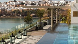 A rooftop infinity pool with a clear view of a coastal town and a prominent tower in the background. - Fairmont Residences La Marina Rabat Sale (Sale)