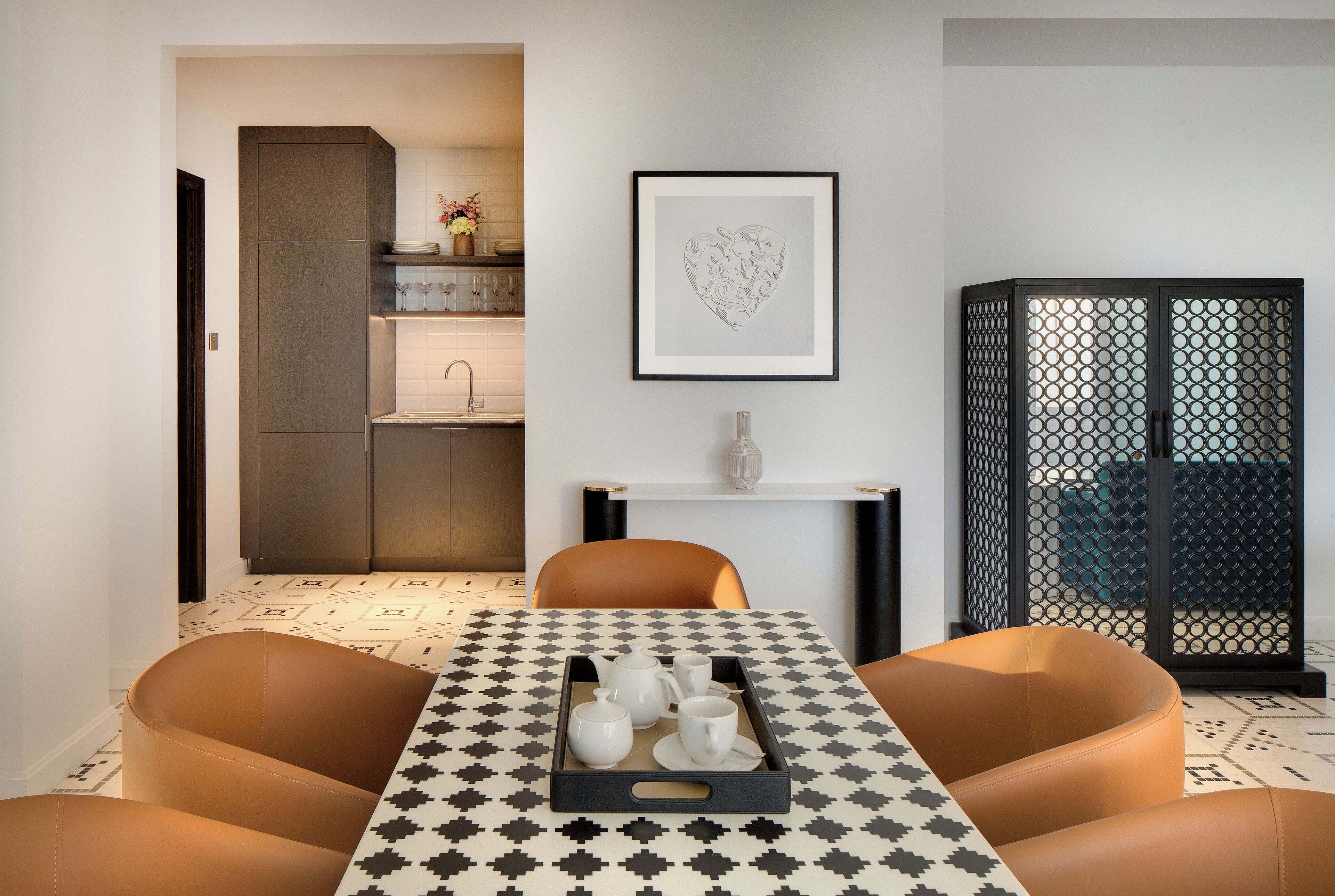 A modern dining area with a checkered tablecloth, a tray with tea set, and a decorative heart art piece on the wall.
