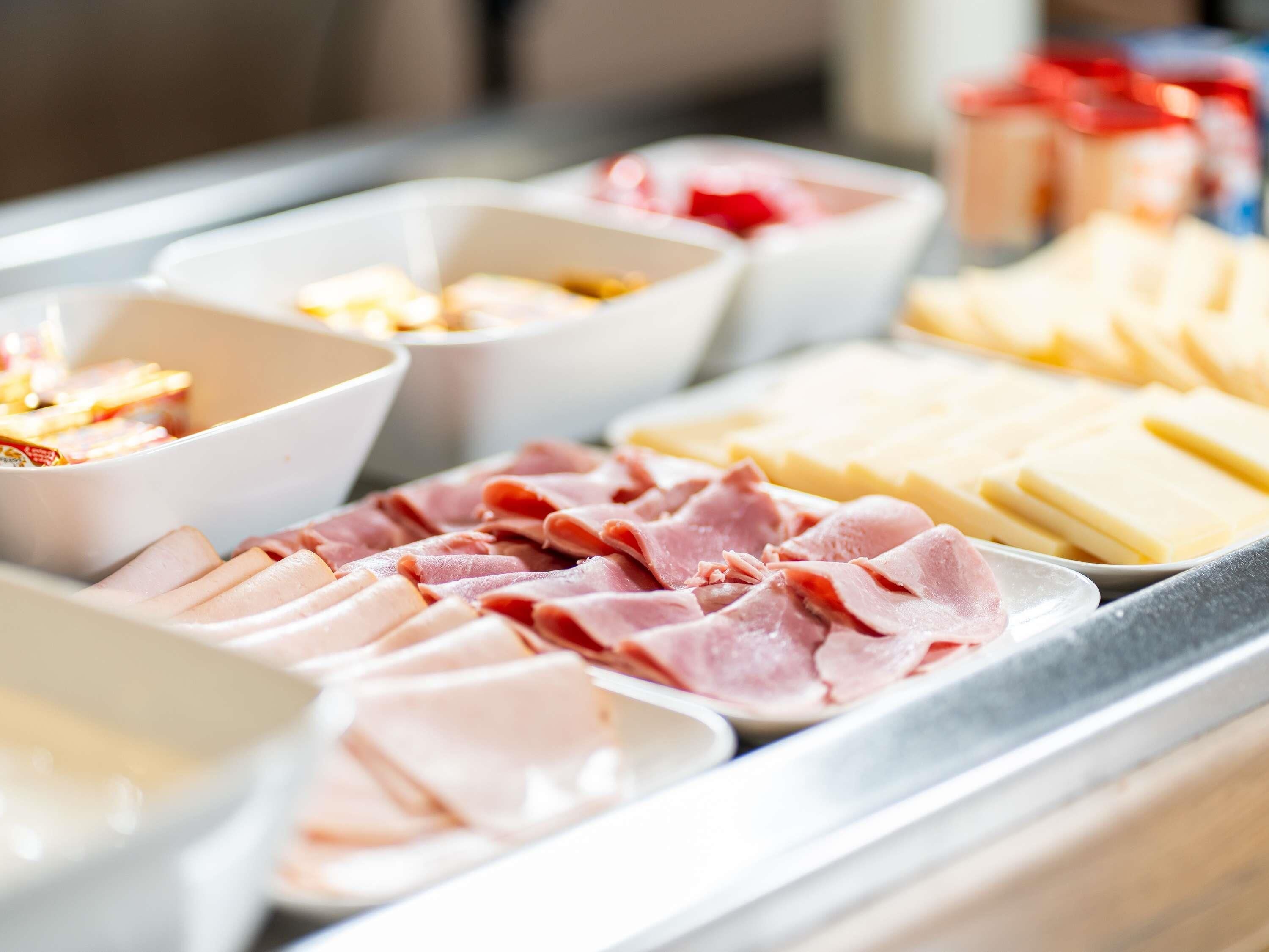 Un bufé con diferentes opciones de comida, incluyendo embutidos y quesos.