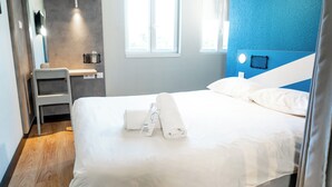 Een hotelkamer met een bed, een bureau, een stoel, een spiegel en een raam.