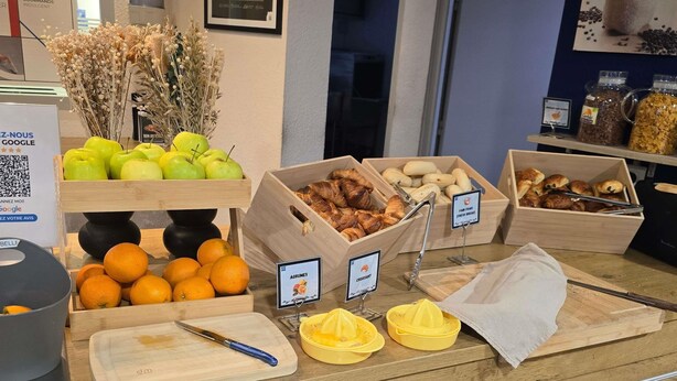 Een ontbijtbuffet met vers fruit, brood en juicedispensers.