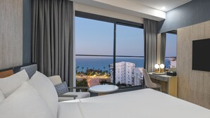 Une chambre d’hôtel avec un grand lit, un bureau avec une chaise, une petite table ronde et un téléviseur fixé au mur.