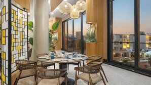 Un espace repas comprenant une table ronde, quatre chaises et des lampes sphériques suspendues.