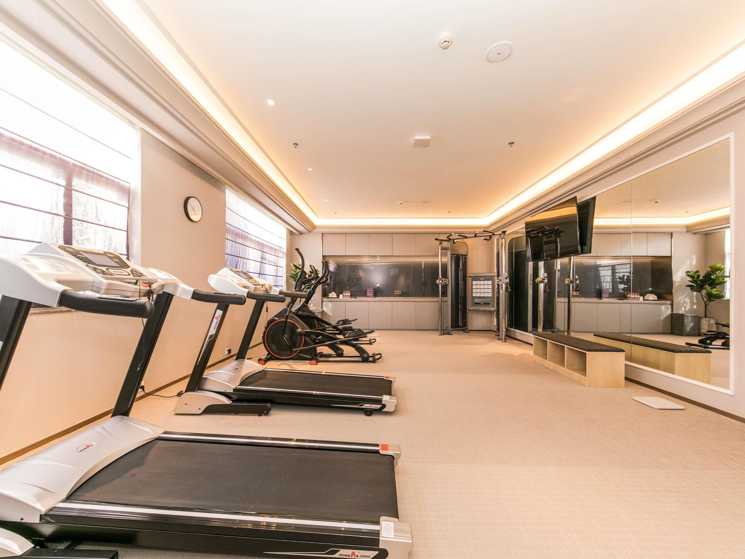 A fitness center with treadmills, a pull-up bar, and a mirrored wall.