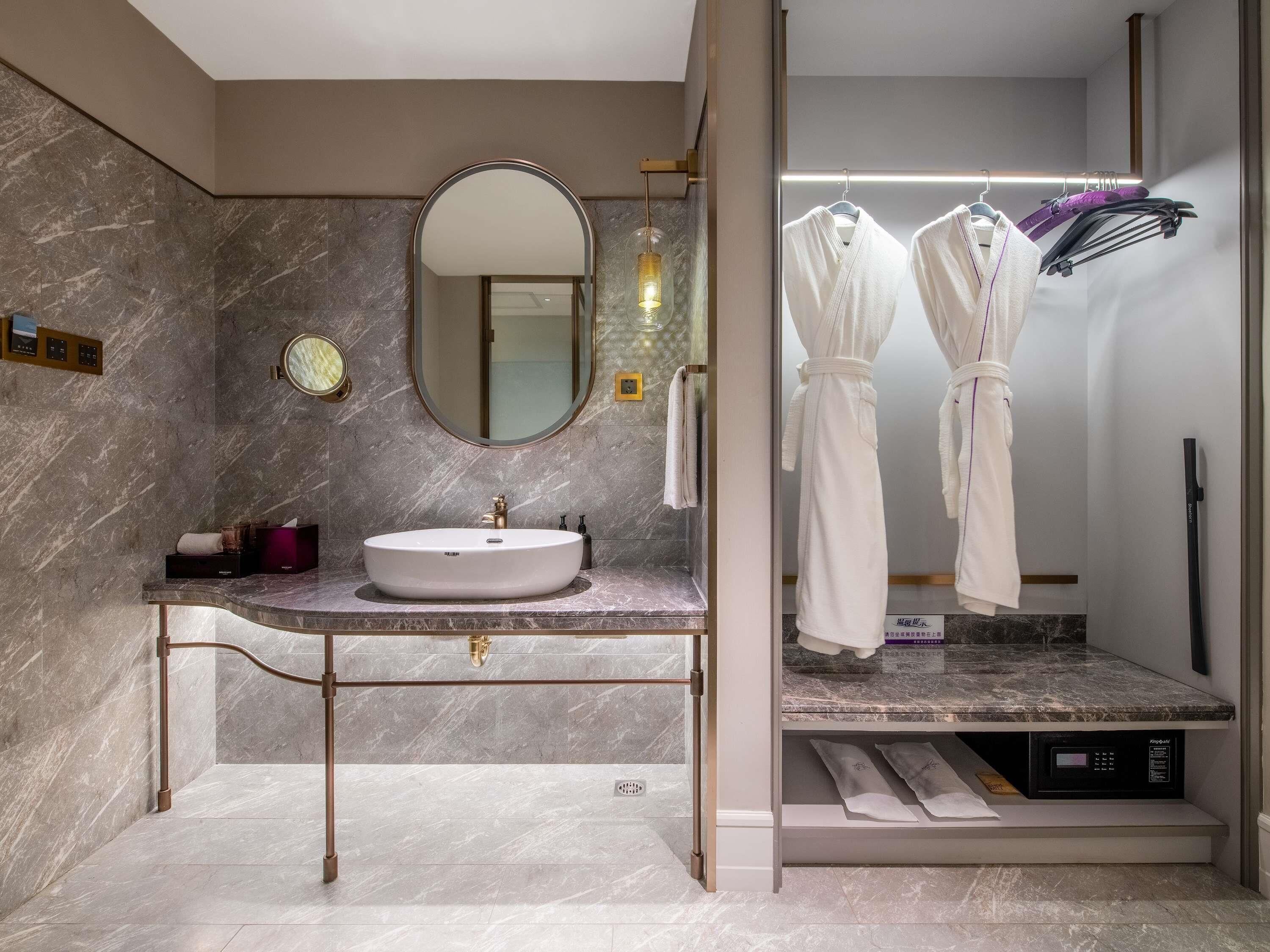 Un baño moderno con lavamanos de mármol, un espejo grande y un tendedero para toallas.