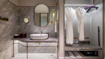 Un baño moderno con lavamanos de mármol, un espejo grande y un tendedero para toallas.