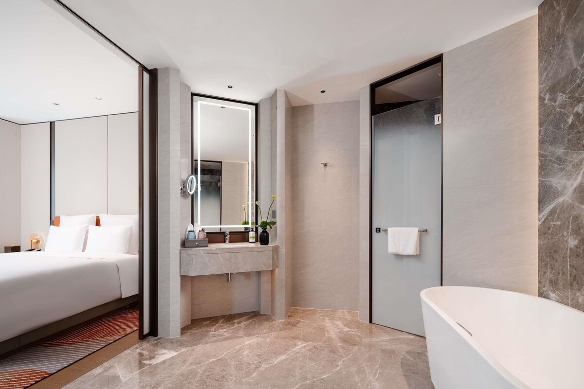 Un baño moderno con bañera, un espejo grande y un inodoro.