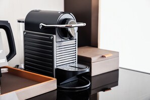 Une machine à expresso compacte au design élégant et noir, dotée d’un réservoir d’eau en acier inoxydable et d’un bac en cuir marron.