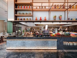 A modern kitchen with a chef preparing food, a variety of fresh produce, and neatly organized shelves with jars and containers.
