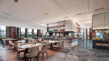 Een ruim restaurant met hoge plafonds, een centrale bar en uitzicht over de stad.
