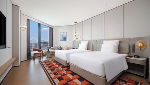 Une chambre d’hôtel moderne équipée de deux lits, d’un bureau, d’une chaise et d’une grande fenêtre donnant sur la ville.