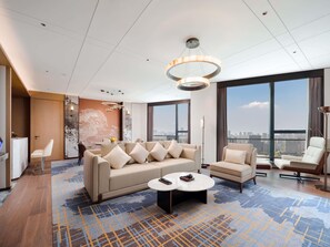 Een moderne hotelkamer met een grote bank, een bijzettafeltje en uitzicht op de stad.