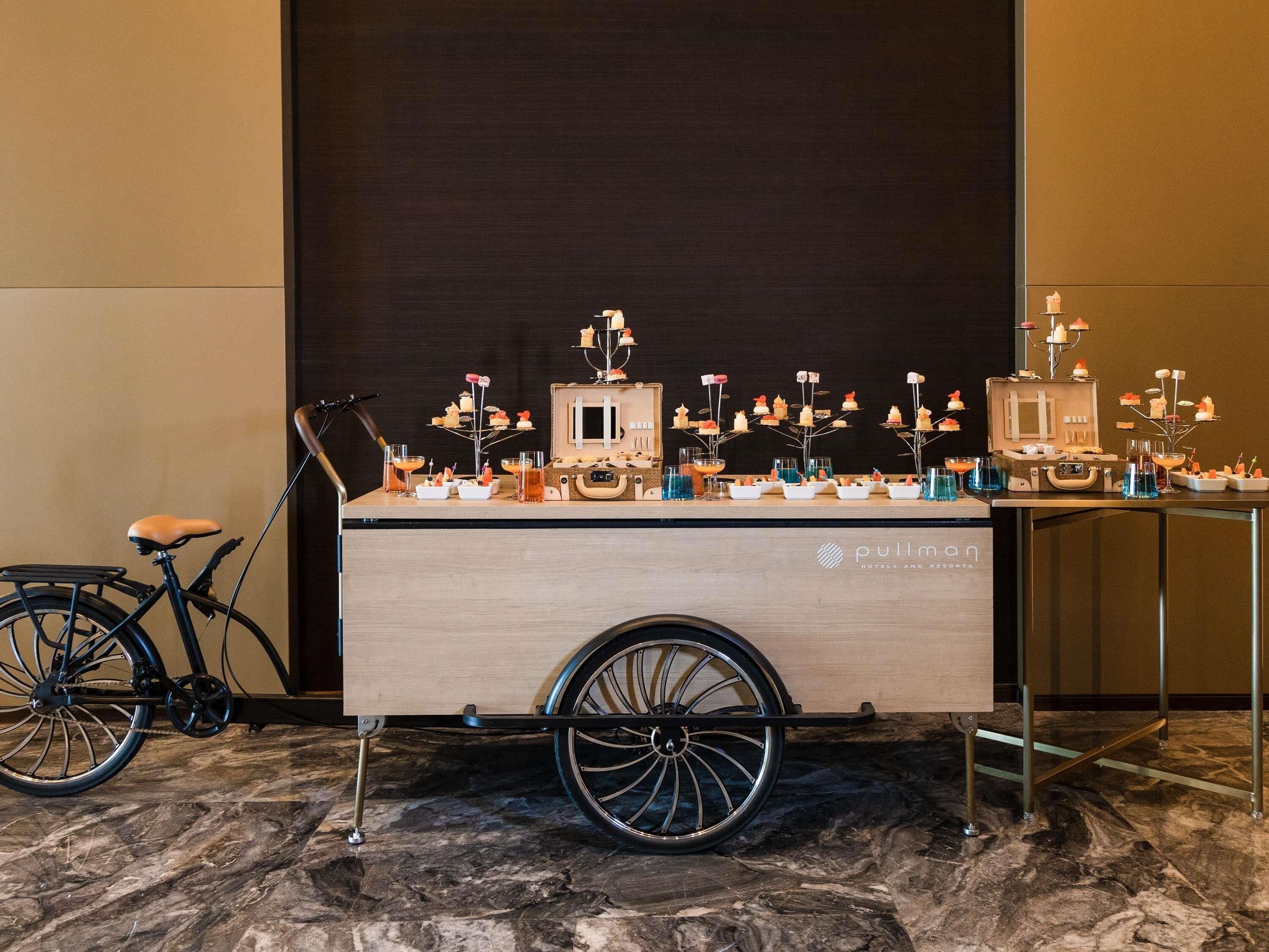 A pullman branded cart with a wooden finish, wheels, and a handle, placed on a marble floor.
