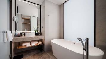 A modern bathroom with a freestanding bathtub, a large mirror, and a vanity with a sink and towel rack.
