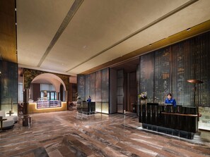 A spacious lobby with a marble floor, reception desks, and a view of the city through large windows.